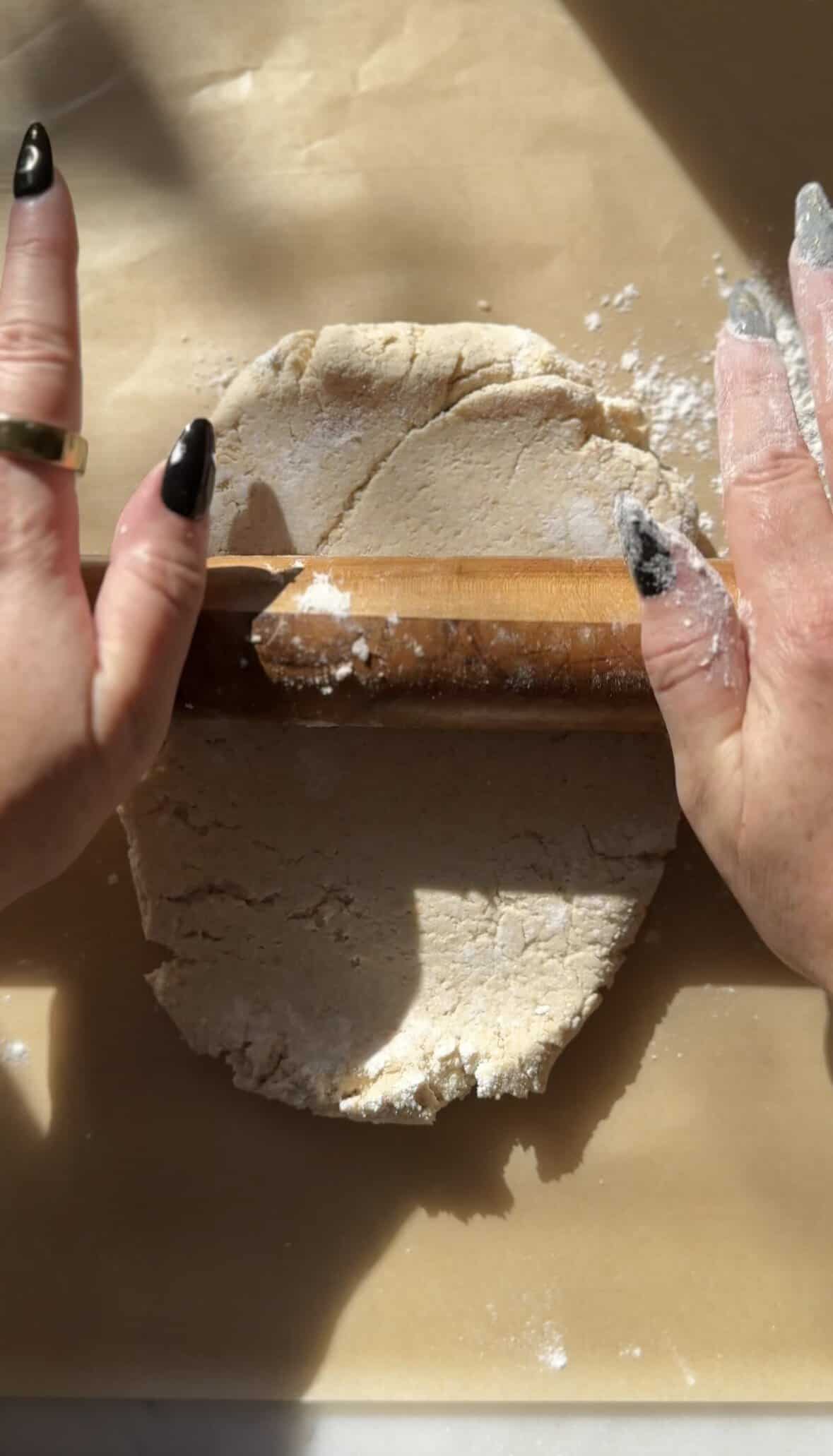 Rolling out the gluten-free cinnamon roll dough on a floured parchment paper.