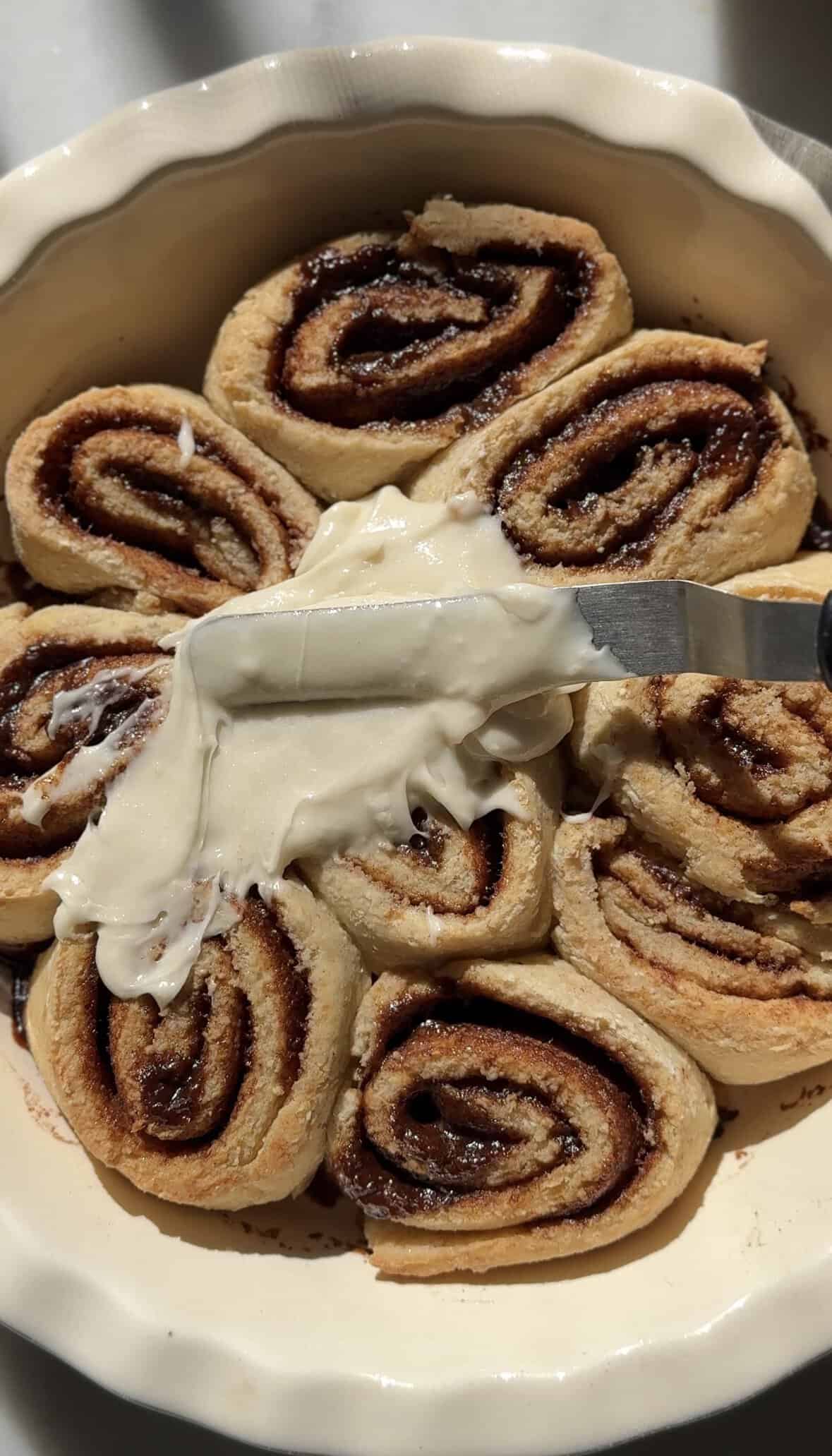 Frost the eight gluten-free cinnamon rolls in a baking dish with the cream cheese frosting.