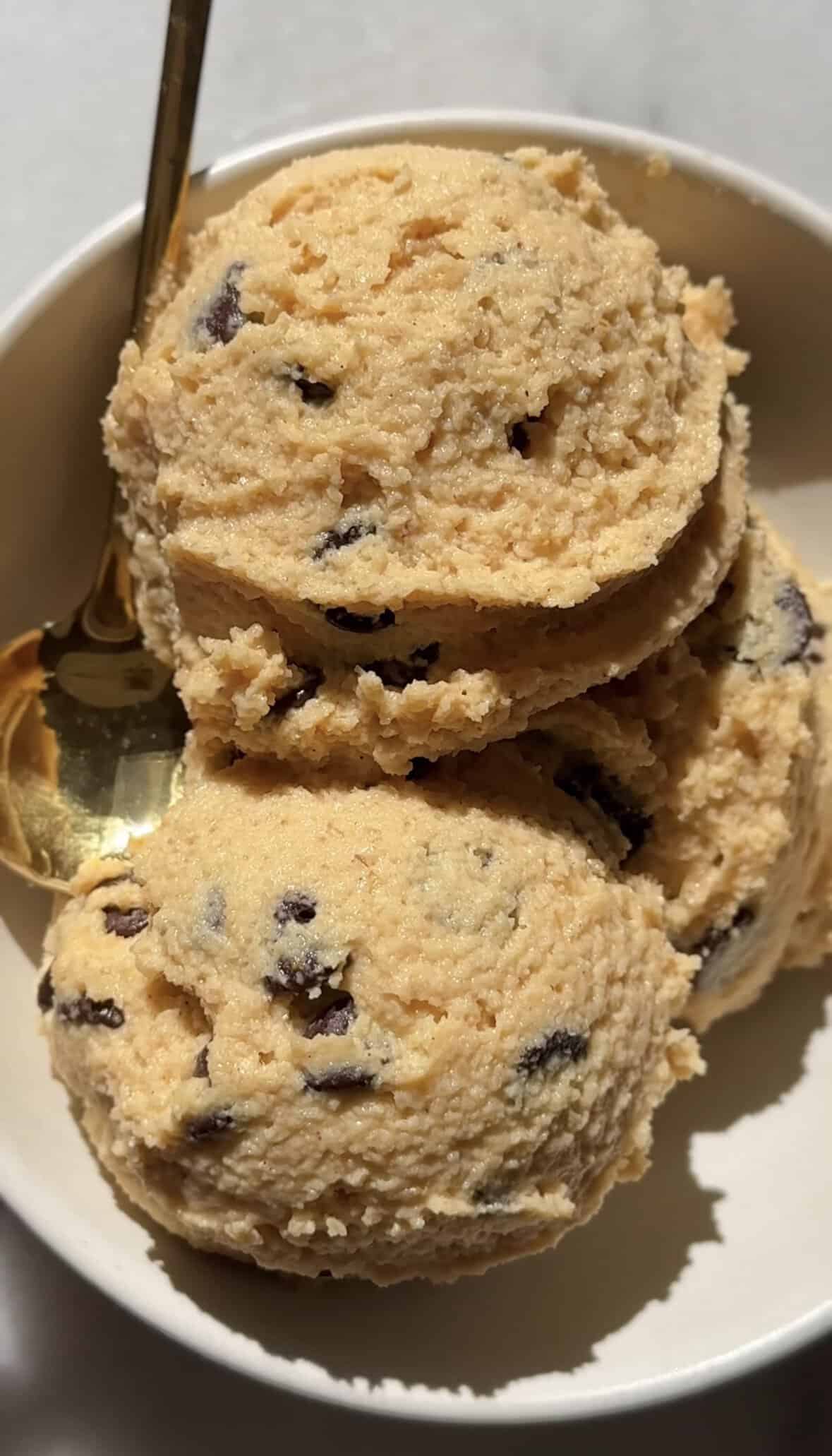 Three scoops (one serving) of Pumpkin Cottage Cheese Cookie Dough in a bowl with a spoon.