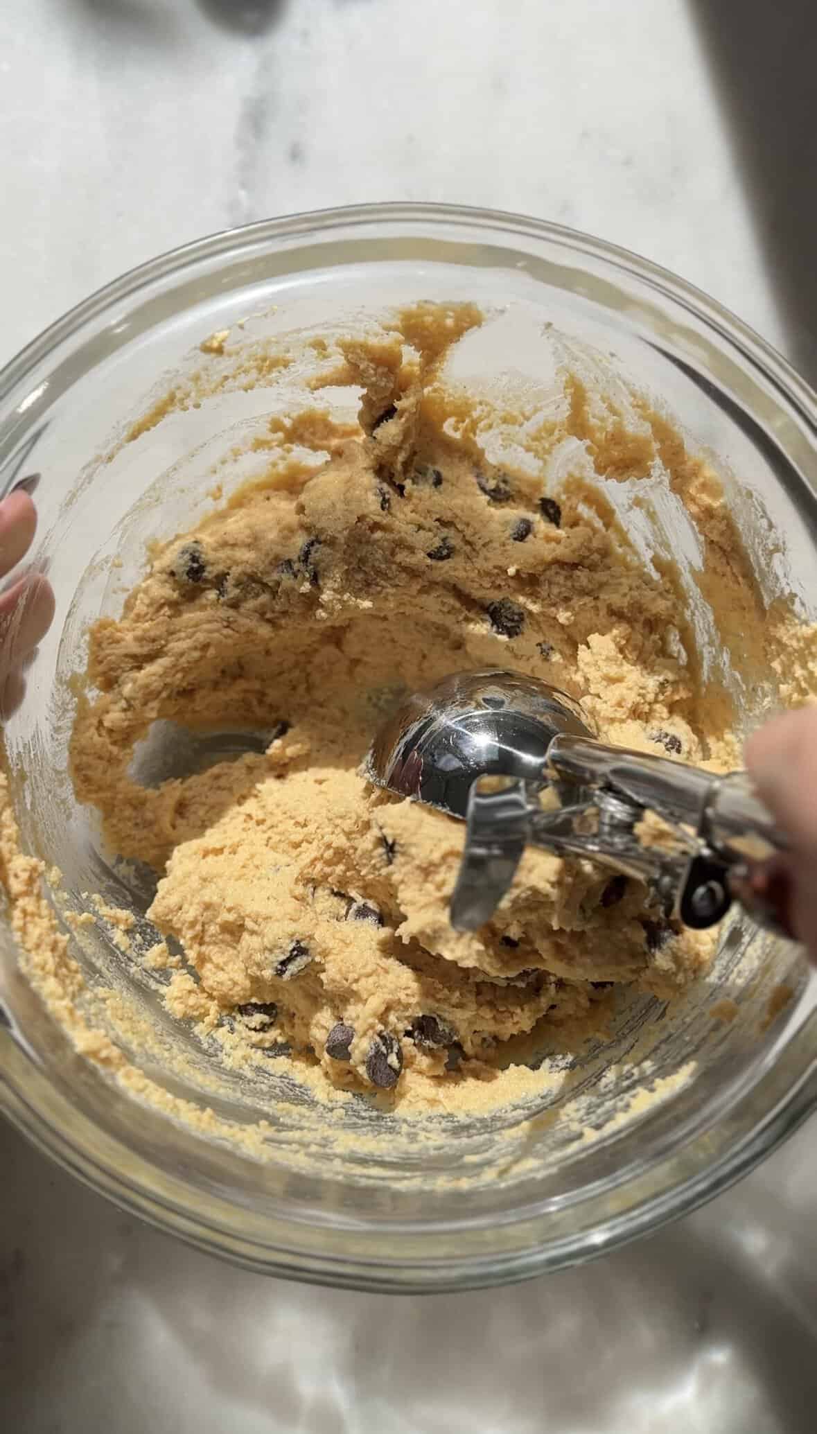 Scooping Pumpkin Cottage Cheese Cookie Dough with a cookie scoop immediately after the dough was made.